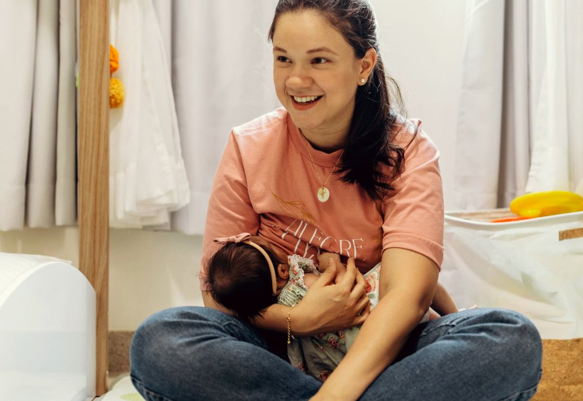 Mãe sentada no quarto do bebê com a filha no colo