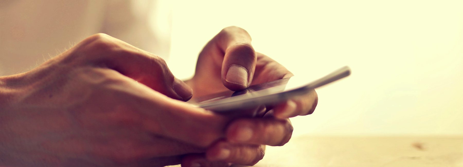 Mãos seguram o celular sobre a mesa