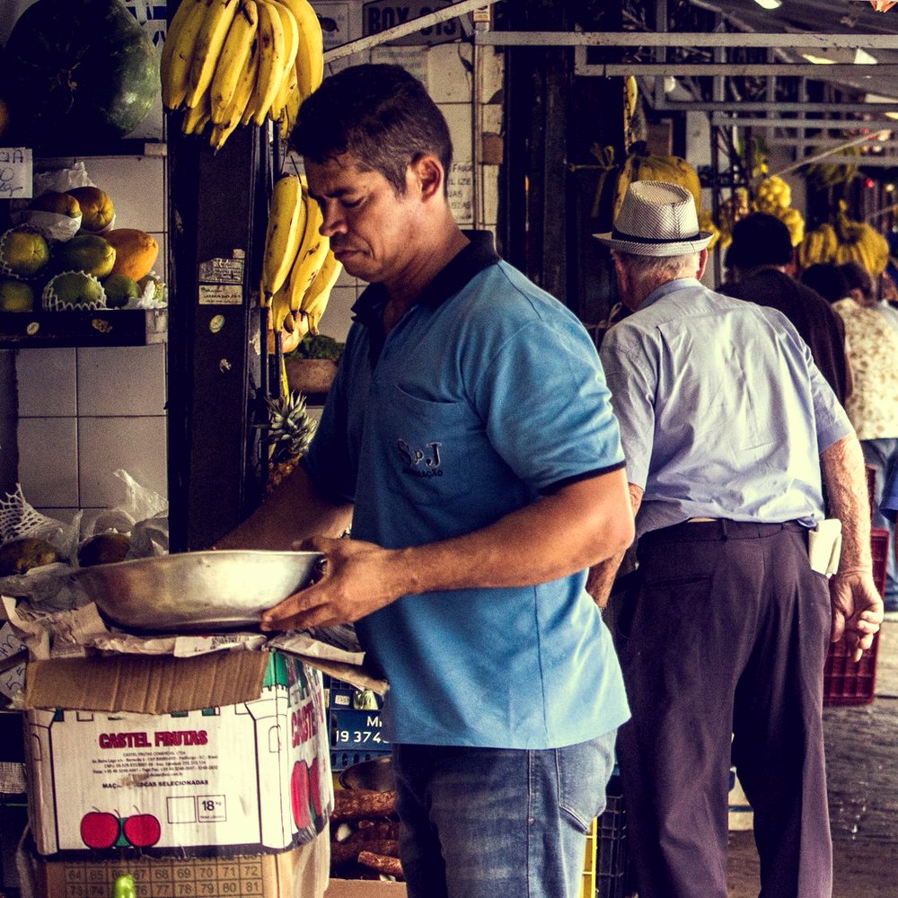 Feirante atende os fregueses na banca de frutas